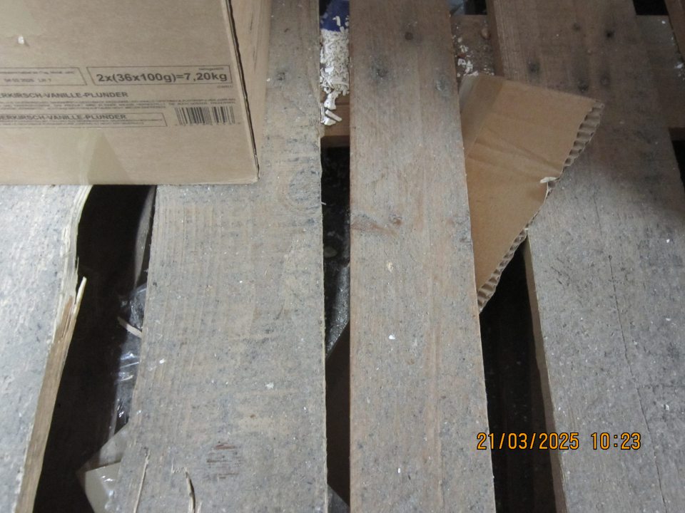 V sklade pre hlbokozmrazené potraviny pod paletami hrubá vrstva organických nečistôt vrátane zbytkov pekárskych výrobkov určených k dopeku, zbytky kartónov a nánosy prachu.