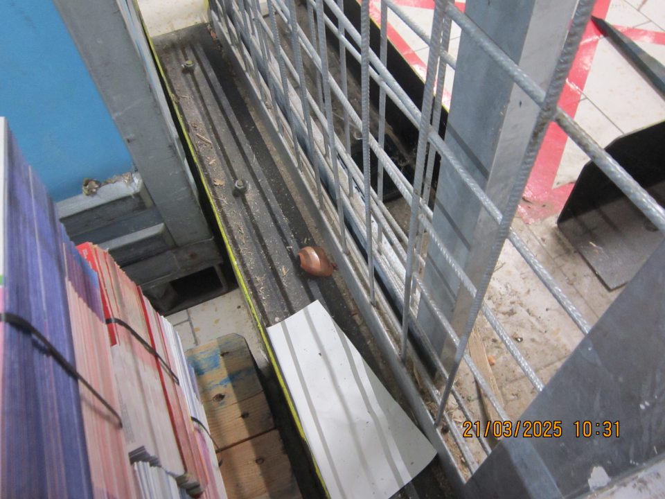 Podlaha znečistená prachom, trieskami, zaschnutou špinou a šupkami z cibule v okolí mreže v zóne pre dodávku nočného tovaru. 