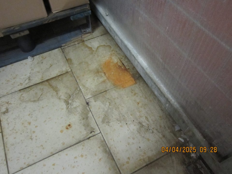 V priestoroch skladu v zázemí, kde je vyhradený priestor výlevky s čistiacim strojom za plastovou zástenou oddeľujúcou uvedený priestor, podlaha  znečistená zaschnutou tekutinou a nečistotou.