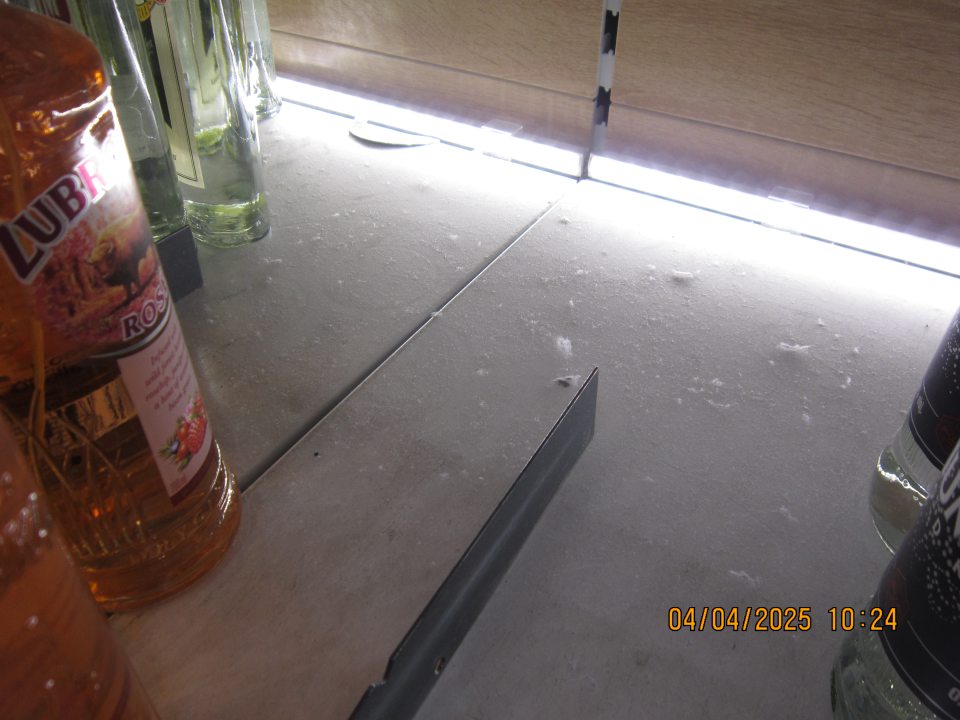 Regály určené na uchovávanie alkoholických nápojov na predajnej ploche znečistené zaschnutou čiernou špinou a prachom.