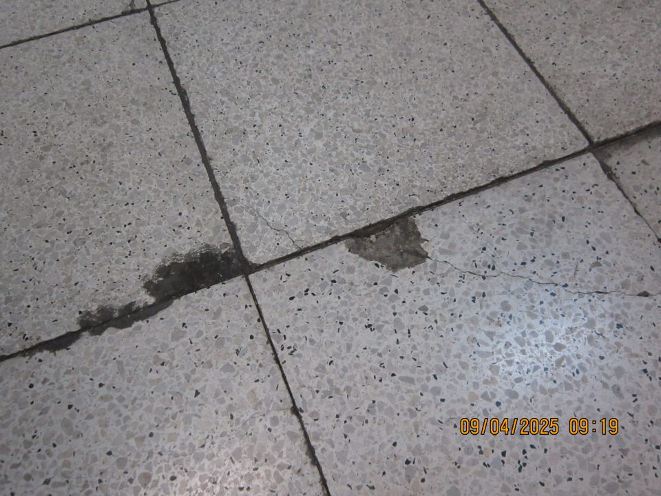 Poškodená dlažba pred príjmovou rampou v skladovacích priestoroch prevádzky. 