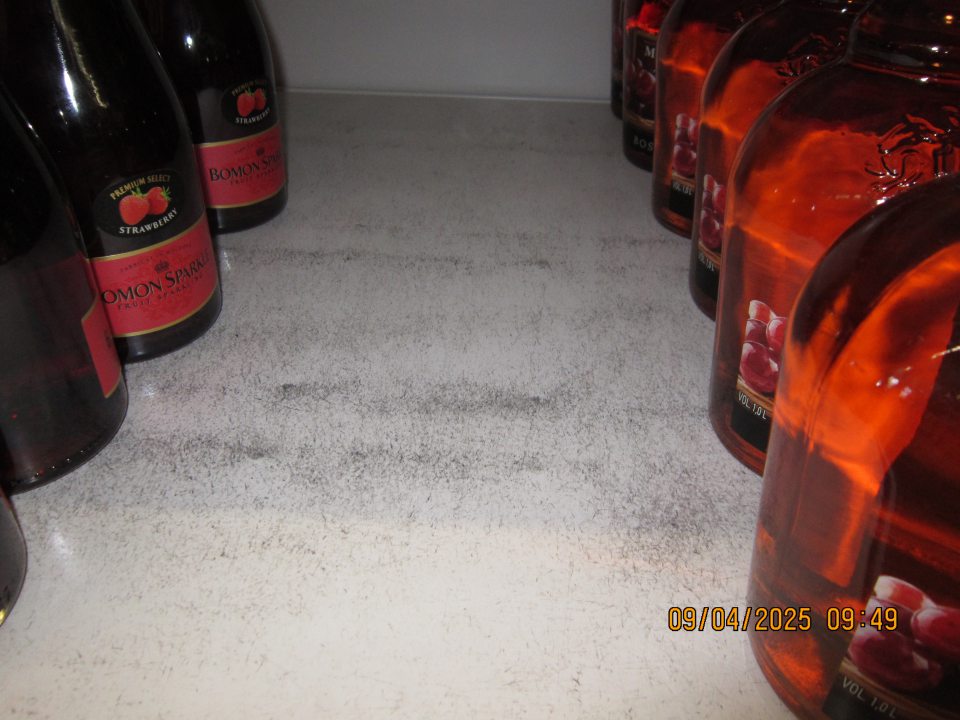 Hygiena zariadení- znečistený regál na uchovávanie alkoholických nápojov zaschnutou špinou a prachom na predajnej ploche. 