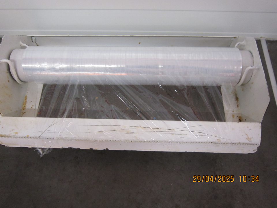 Držiak na baliacu potravinovú fóliu znečistený mastnými nálepmi špiny a zaschnutými drobnými organickými nečistotami.