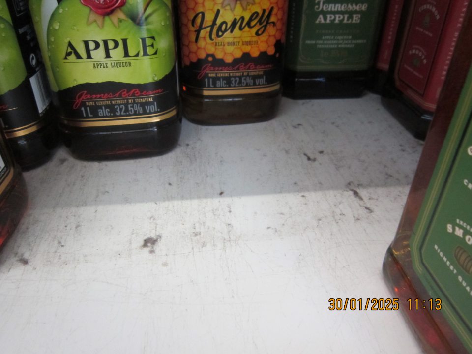 Regály na uchovávanie alkoholických nápojov na predajnej ploche prevádzky  znečistené prachom a čiernou špinou. 