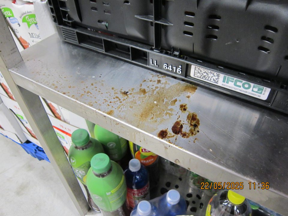 Regál na uchovávanie ochutených nealkoholických nápojov  v skladovacej časti  prevádzky  znečistený zaschnutými nečistotami z vytečeného obsahu z daných výrobkov. 