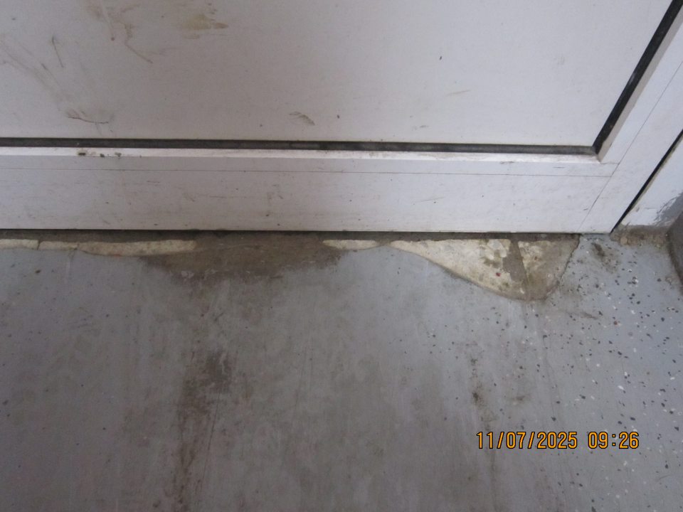 V zázemí prevádzky - poškodená podlaha pri príjmových dverách.  