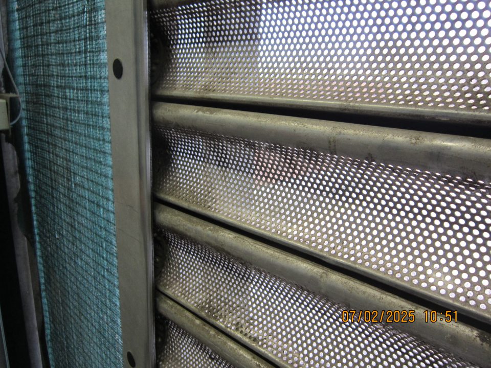 V príjmovej časti prevádzkarne silné znečistenie kovovej rolovacej brány vrstvou usadeného prachu.