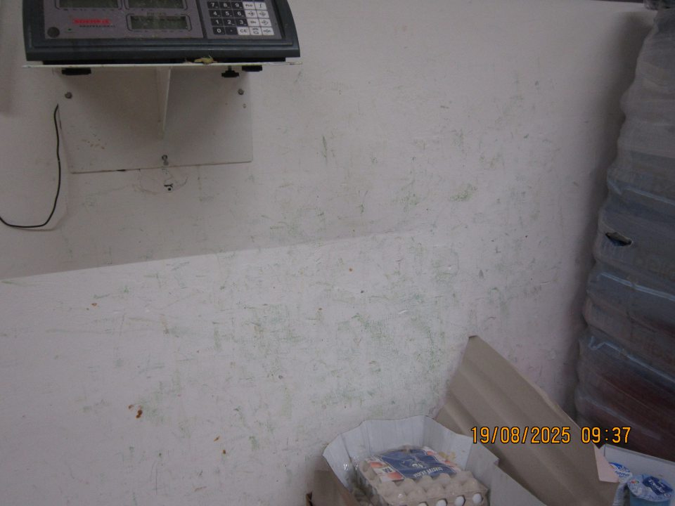 Znečistená a poškodená hygienická maľba steny pod digitálnou váhou v priestore odpisy v skladovacej časti prevádzky.