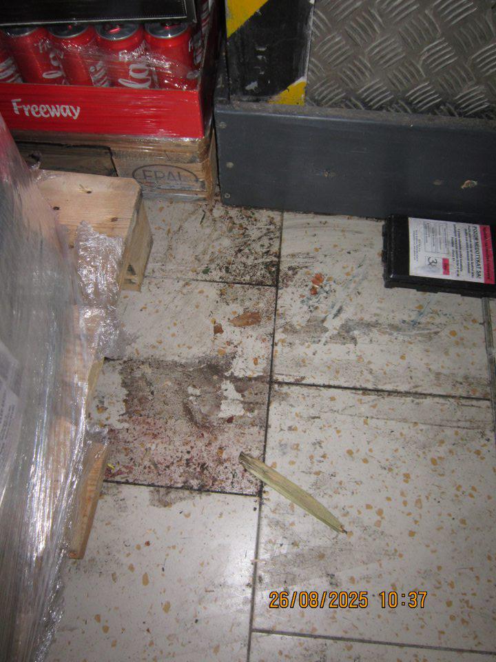 Lepkavá a znečistená podlaha pri paletách s kolovými nápojmi v skladovacej časti prevádzky.