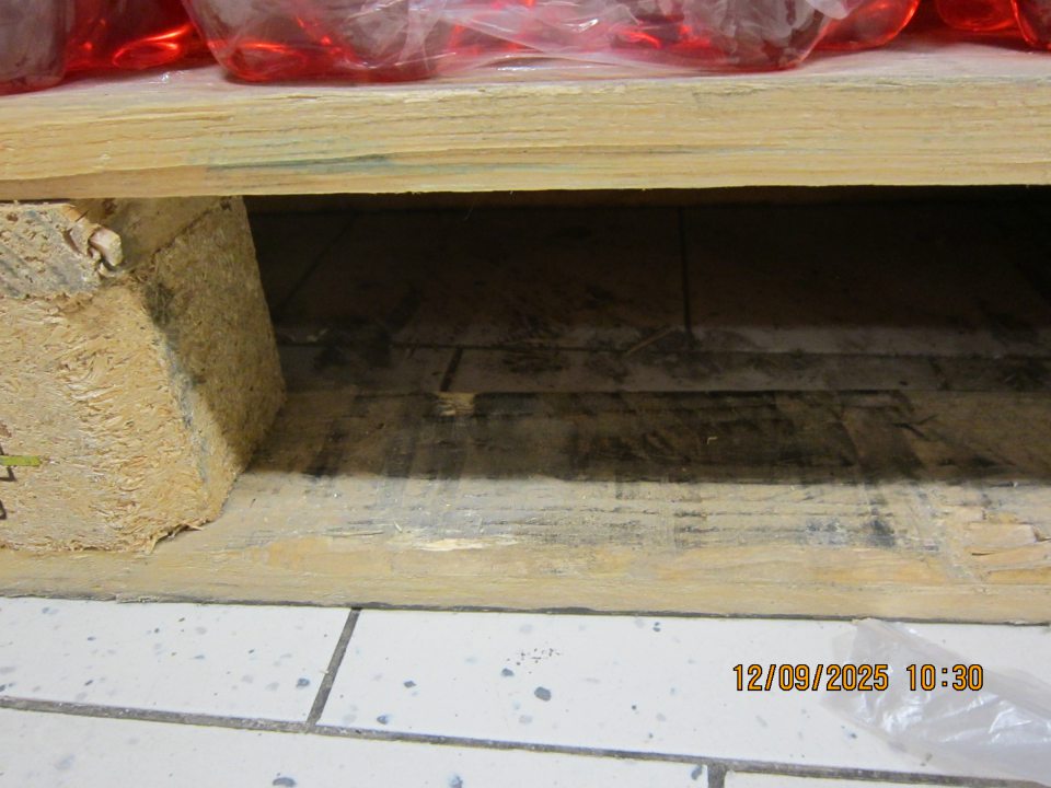 Podlaha na predajnej ploche pod paletami s ochutenými minerálnymi vodami znečistená vrstvou špiny.