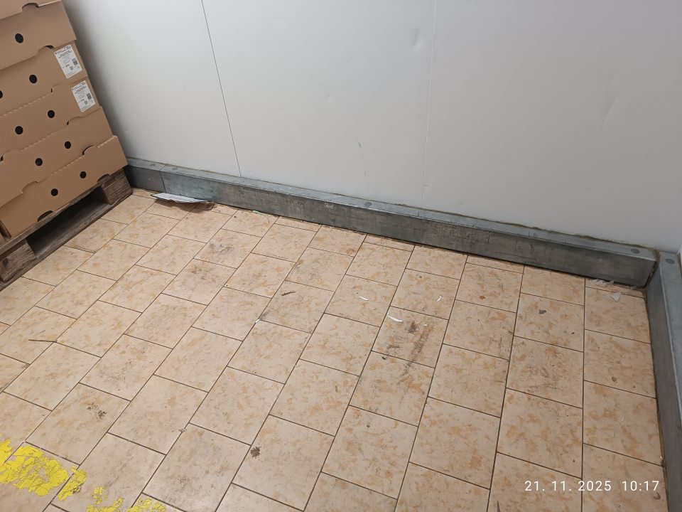  Znečistená podlaha v zázemí v časti chladiaceho boxu čerstvého mäsa a hydiny- mechanickými nečistotami (zvyšky kartónov) a čiernym znečistením). 