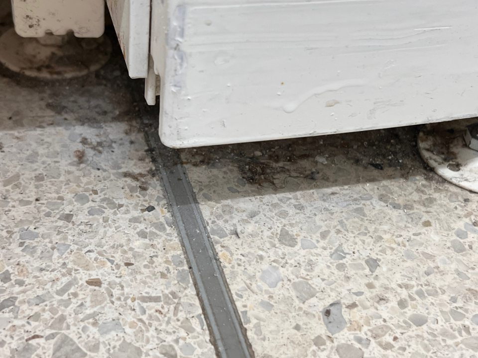 znečistenie podlahy na predajnej ploche pod regálmi s potravinami, hlavne v časti pri nožičkách regálov, zvyškami potravín, obalových materiálov, prachom a nálepmi špiny
