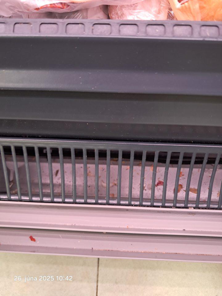 Znečistený priestor pod mriežkami chladiacej vitríny.