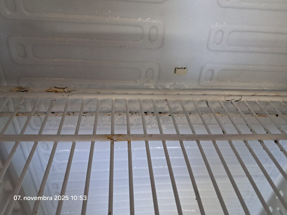 Znečistená a hrdzavá polica v chladničke.