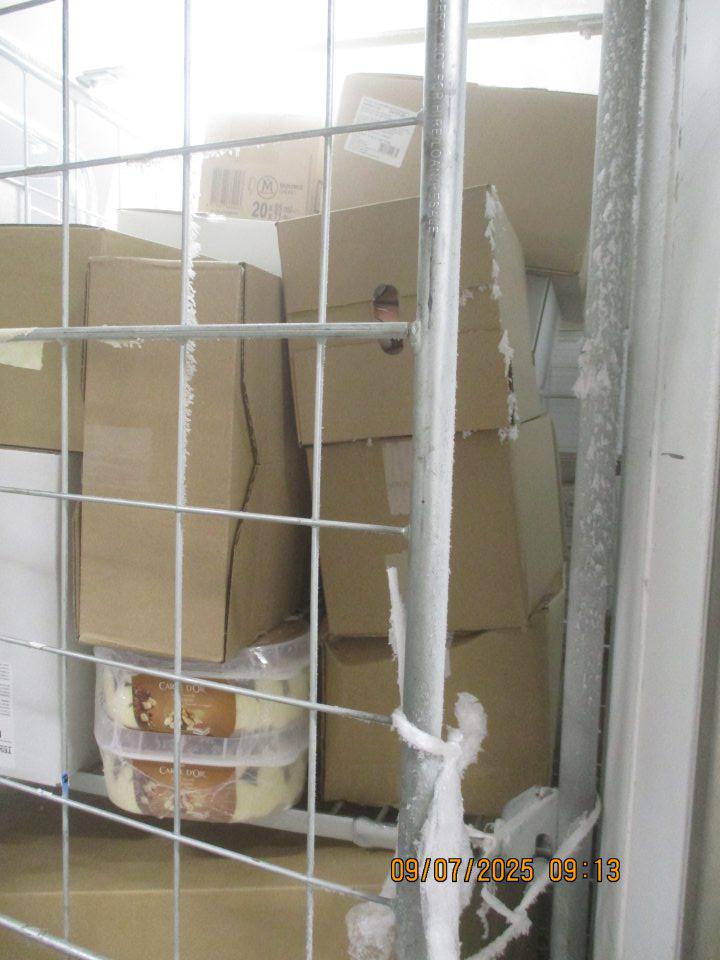  V zázemí: V mraziacom boxe označenom ako „Sklad mrazených výrobkov“ s uloženými hlbokozmrazenými potravinami a mrazenými krémami, zistený výskyt hrubej námrazy na vrchnej zárubne dverí boxu a na bočnej strane klietky. 