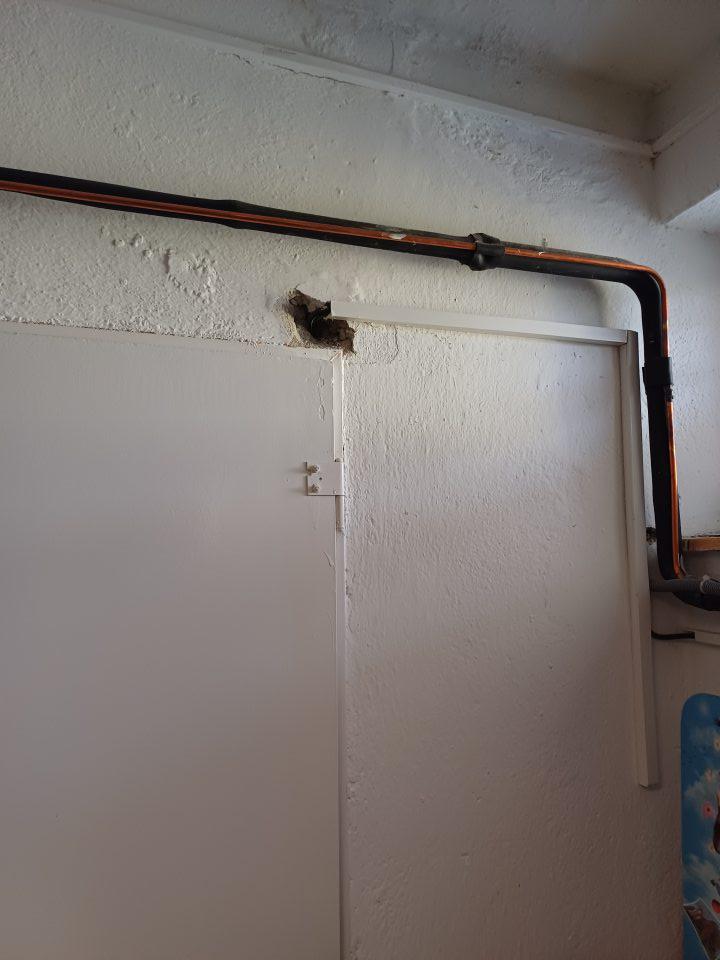 Suchý sklad potravín- poškodená stena, opadáva omietka- pri dverách.