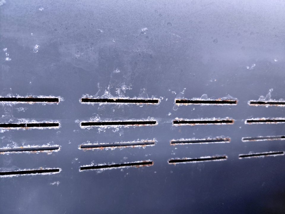 Na zadnej stene chladiaceho zariadenia na mäsové výrobky - okolo vetracích otvorov hrdza.