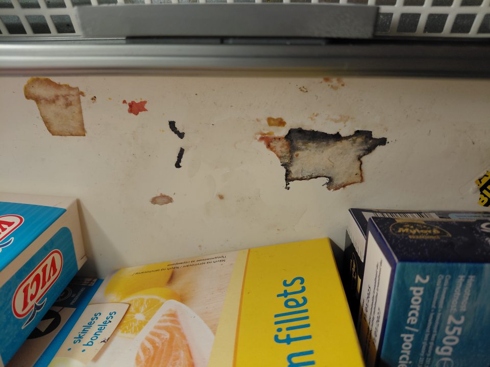 Mraziaci box - znečistena polica (zvyškami nalepených kartónových obalov, omrvinkami).