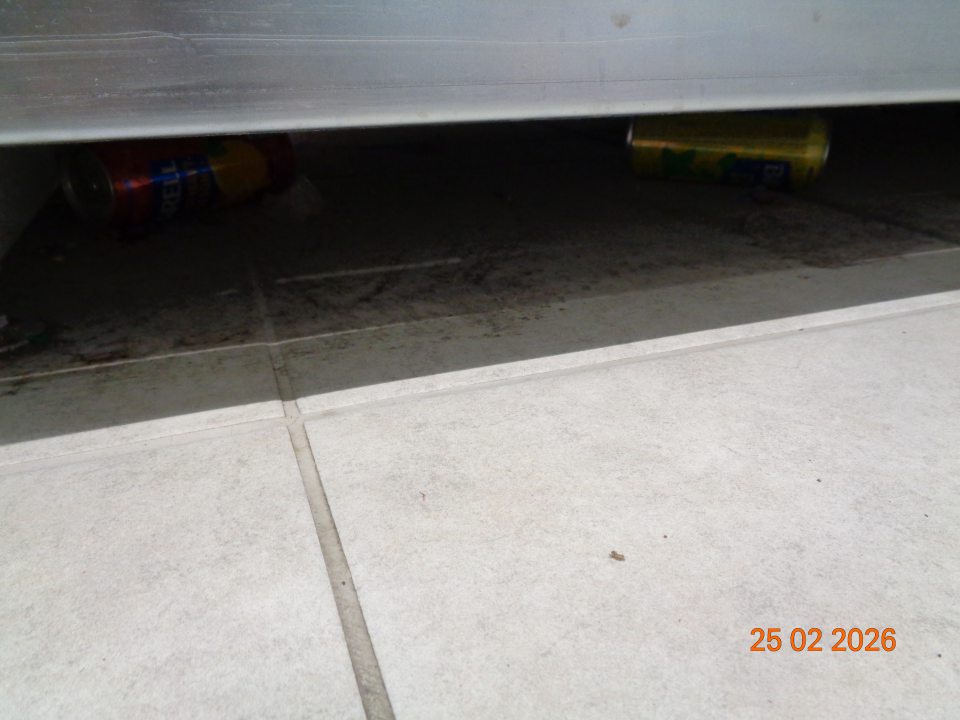 Nálepy čiernej špiny, nečistoty, plechovky pod regálom s pivom na predajnej ploche prevádzky.