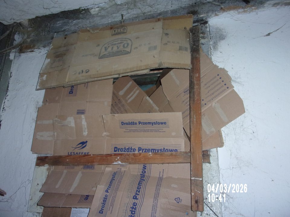 Kartónmi prekrytý otvor v stene do vonkajšieho priestoru v technickej miestnosti prevádzky, ktorá komunikuje s výrobným priestorom.