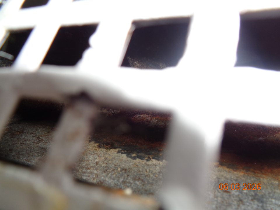 Silné znečistenie priestoru pod mriežkou vrstvou špiny a prachu v chladiacom zariadení na uchovávanie chladeného ovocia a zeleniny.