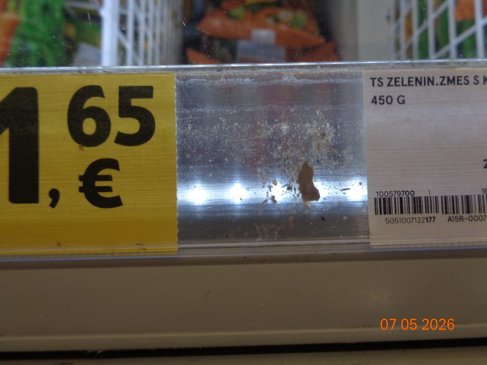 Nečistoty a špina pod plastovými lištami na cenovky na mraziacom boxe určenom na uchovávanie hlbokozmrazenej zeleniny.