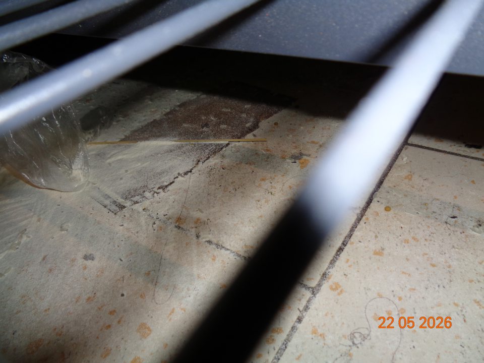 Znečistená podlaha rozsypanou múkou, nečistotami, prachom pod regálom na uchovávanie suchého potravinového tovaru na predajnej ploche.