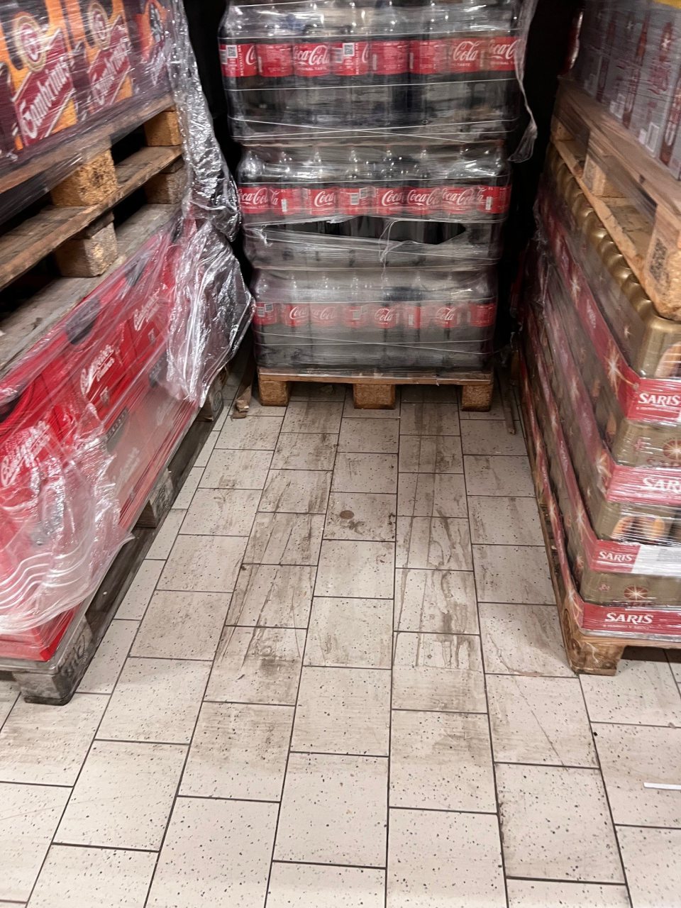 V priestore suchého skladu znečistenie podlahy, hlavne v častiach medzi paletami a pod paletami s potravinami, pozdĺž okrajov stien a drevených zábran nálepmi špiny, rozsypanými potravinami a poškodenie okrajových drevených zábran v tomto sklade.