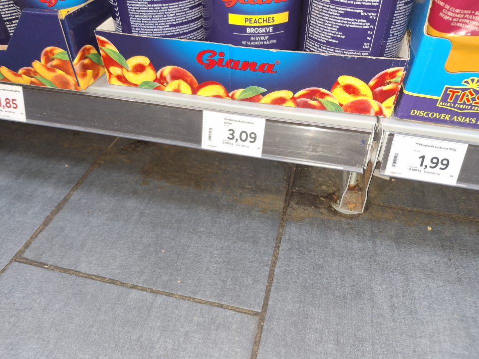 Znečistená podlaha v predajni na viacerých miestach hrubou vrstvou prachu, papierikmi a zaschnutými nečistotami.