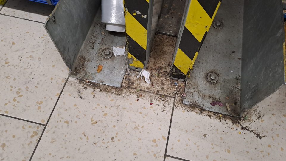 Podlaha v zázemí kde sa skladujú potraviny je na viacerých miestach znečistená hrubou nečistotou, , zvyškami obalového materiálu.