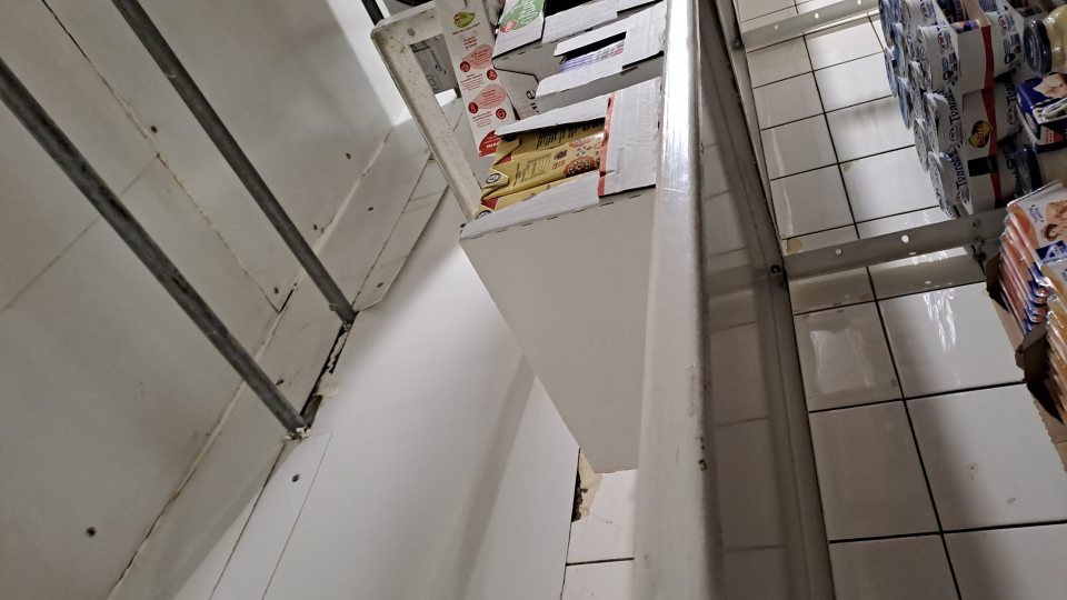 2.Chladiarenský box v zázemí prevádzky určený na skladovanie mliečnych výrobkov má stenu na viacerých miestach poškodenú a to v časti obloženia pri kovovej konštrukcii a v časti keramického obkladu - obkladačky sú poškodené a opadávajú a znečisťujú ložnú plochu regálu.